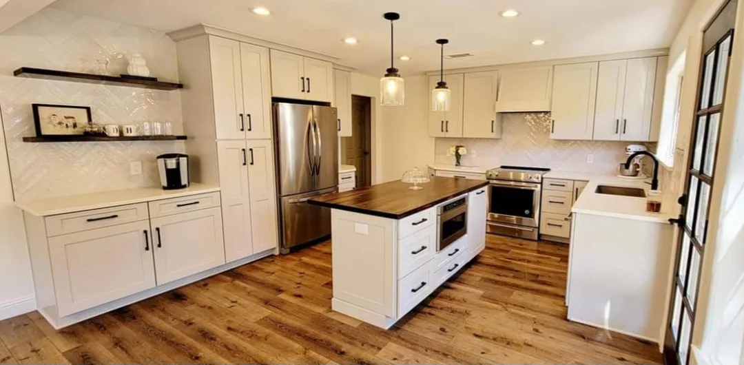 After: full kitchen remodel with white shaker cabinets, herringbone tile, and a wood-top island