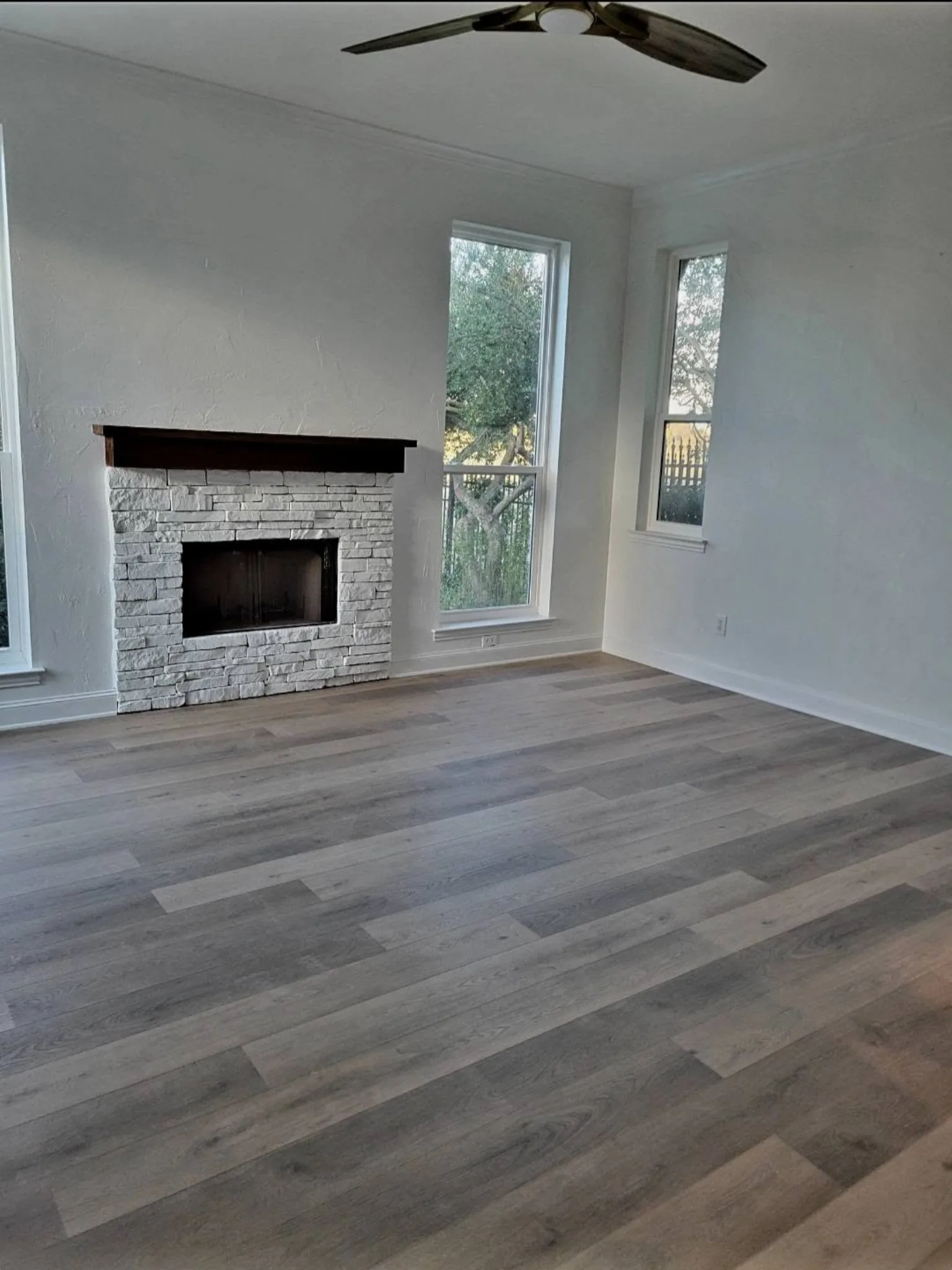 Refinished living room with stacked-stone fireplace and new flooring