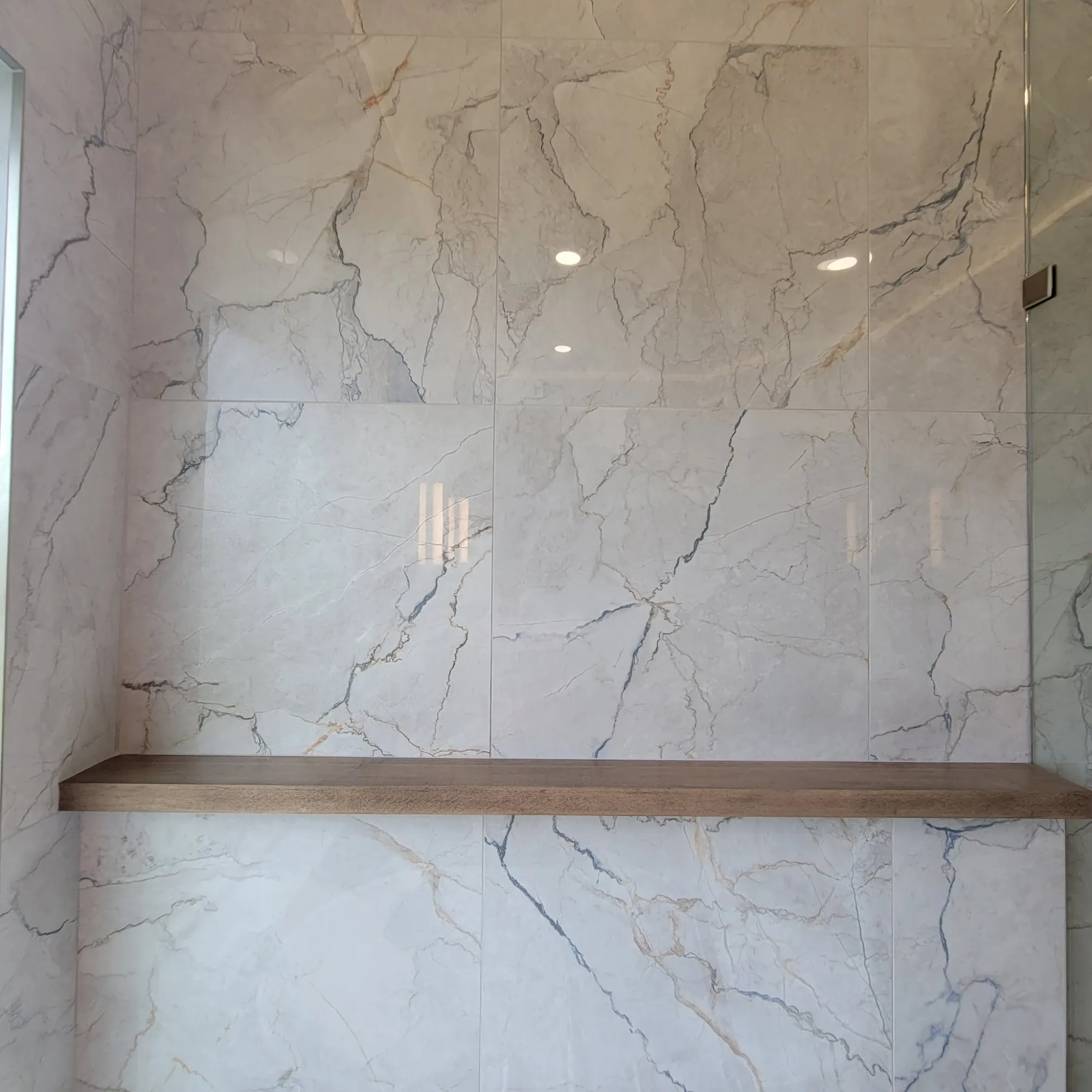 Full-height marble tile with built-in wood shelf