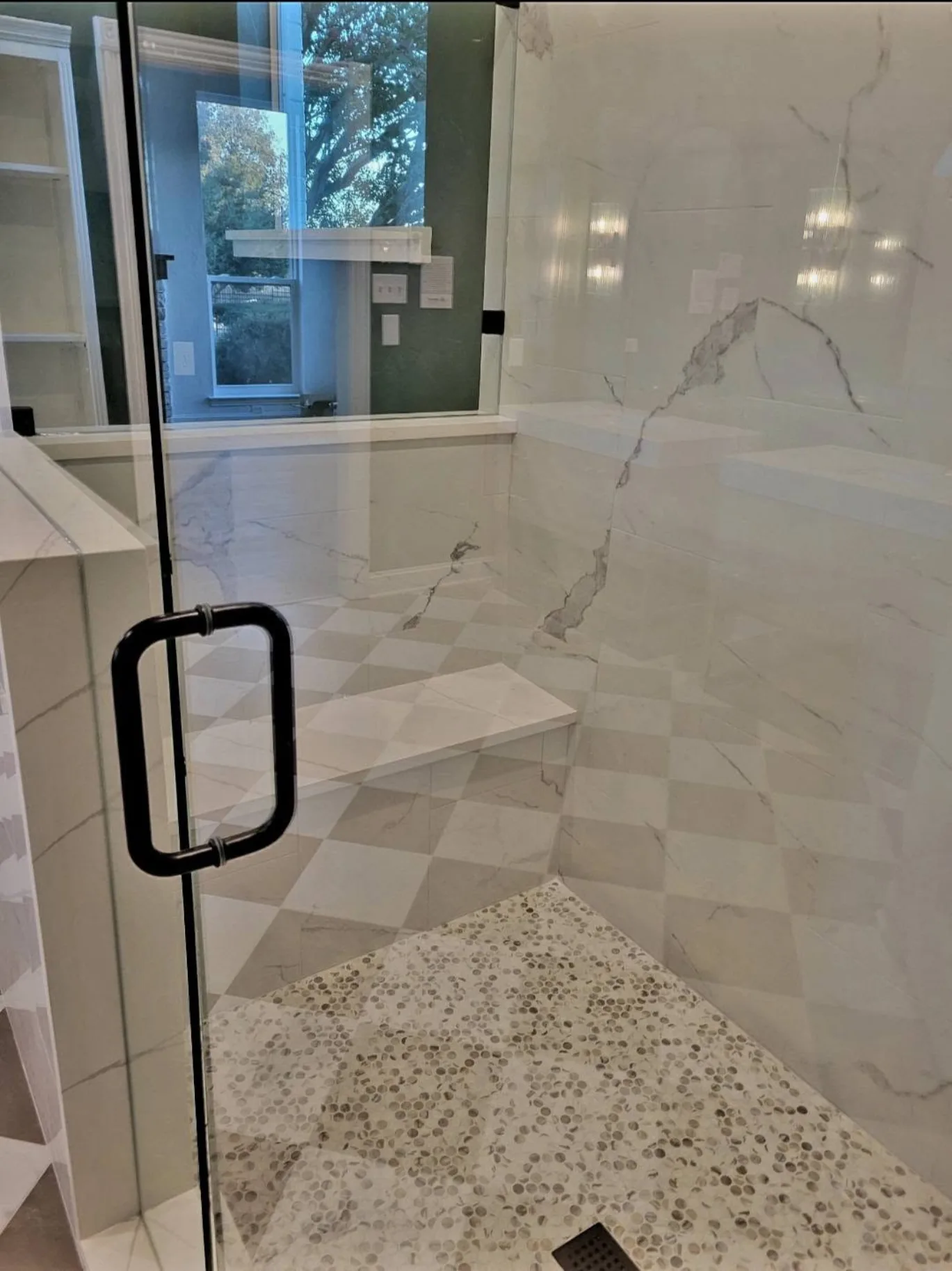 Marble hex-tile shower floor and matte-black fixture detail