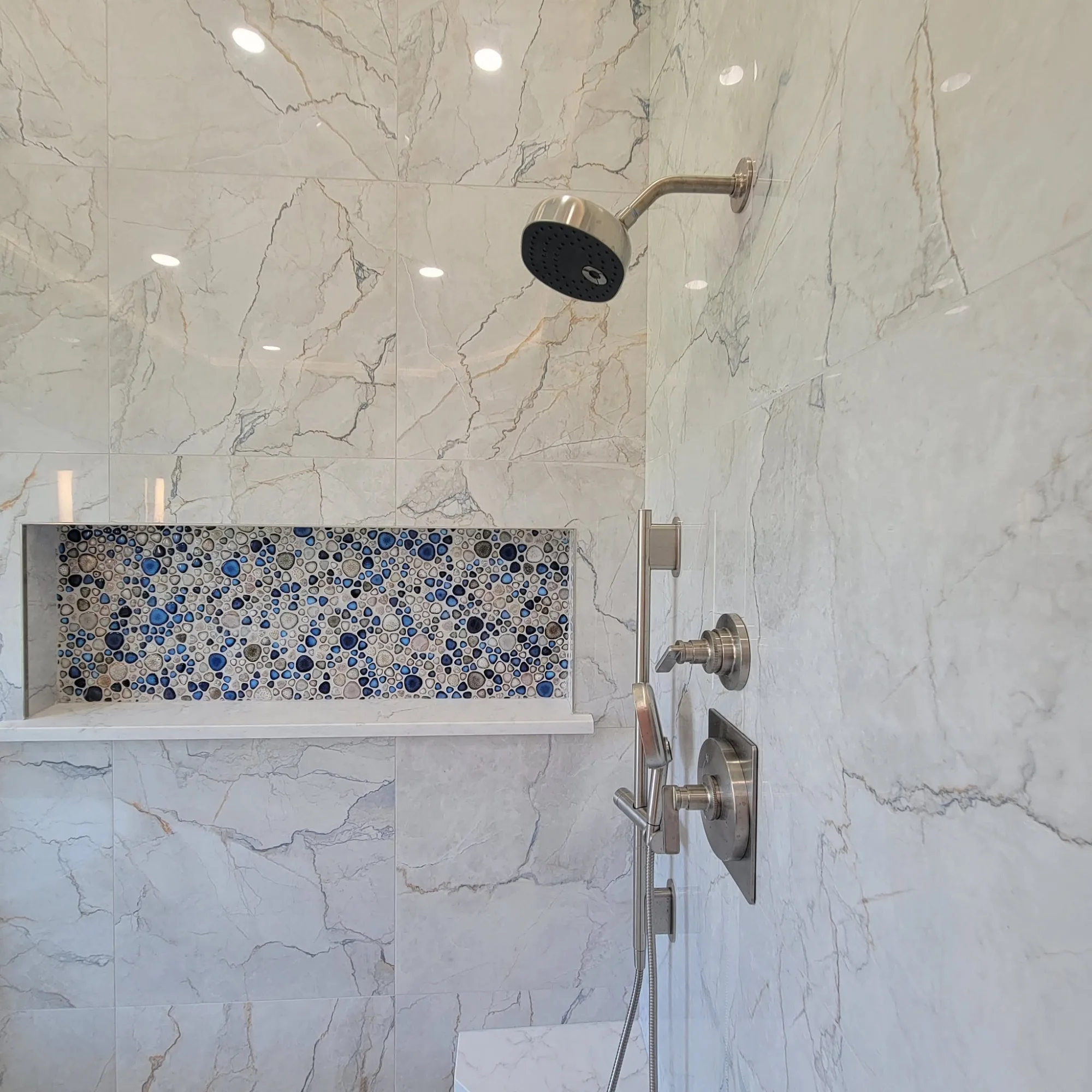 Marble shower with iridescent pebble-mosaic accent niche