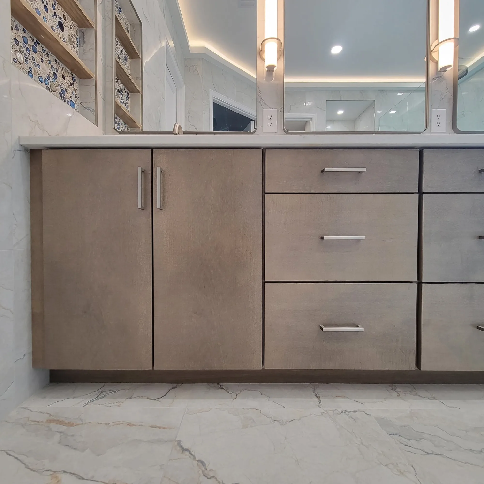 Dual vanity cabinetry with matching pebble-mosaic accent shelving