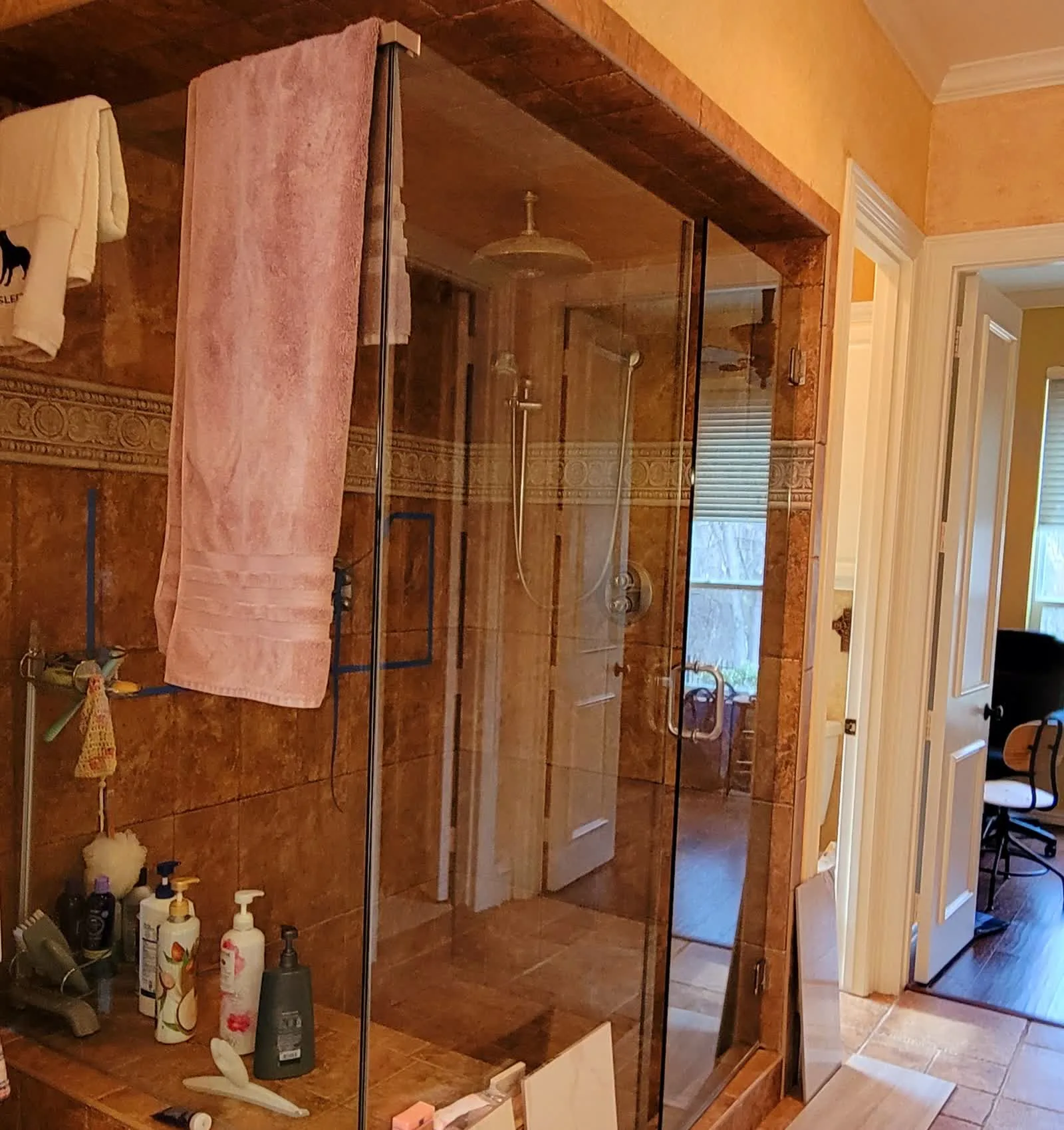 Before: dated corner shower with 1990s tile and brass fixtures